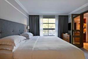 una camera da letto con un grande letto bianco e una finestra di Hyatt Regency London - The Churchill a Londra