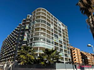 Un edificio alto con palmeras delante. en Aqua Turquesa, en Oropesa del Mar