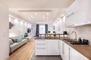 a kitchen and living room with white cabinets and a couch at Downtown Nature Apartment in Budapest