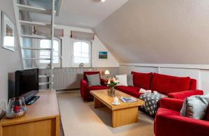 a living room with red couches and a tv at Ferienwohnung Nordwind in Westerland (Sylt)