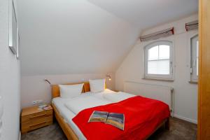 ヴェスターラントにあるFerienwohnung Nordwindのベッドルーム1室(赤毛布付きの大型ベッド1台付)