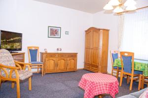 uma sala de estar com cadeiras, uma secretária e uma televisão em Haus Ufen - In den Dünen 18c em Norderney