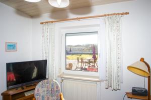 ein Wohnzimmer mit einem Fenster mit Blick auf einen Tisch in der Unterkunft Haus Ufen - In den Dünen 18c in Norderney