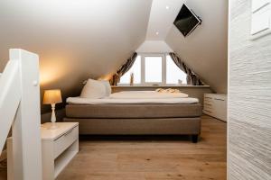 a small attic bedroom with a bed and a window at Ferienwohnung Buhne73 in Wenningstedt