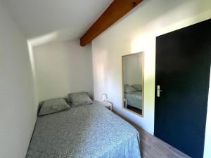 een slaapkamer met een bed en een spiegel aan de muur bij Idéal pour vos vacances a in Aigues-Mortes