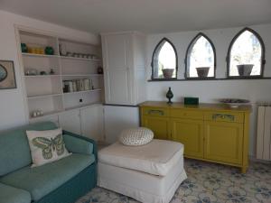 ein Wohnzimmer mit einem Sofa, einem Stuhl und 2 Fenstern in der Unterkunft Villa Piccinina A pochi passi da Villa Eva in Ravello