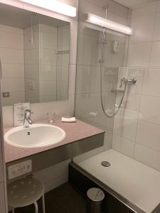 a bathroom with a sink and a shower at Congress Apartments by Hotel du Commerce in Basel