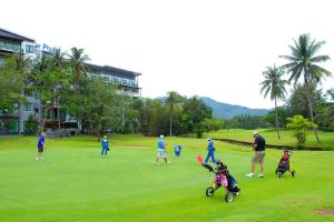 un grupo de personas jugando al golf en un campo de golf en The Par Phuket SHA Plus, en Kathu