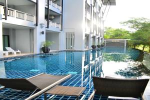 a swimming pool in the middle of a building with chairs at The Par Phuket SHA Plus in Kathu