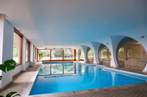 een binnenzwembad met blauw water in een gebouw bij [LUXURY]・VILLA ☆☆☆☆☆・Pool, Sauna and Park in Sedriano