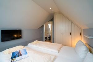 a bedroom with two beds and a tv on the wall at Kleine Buhne in Wenningstedt