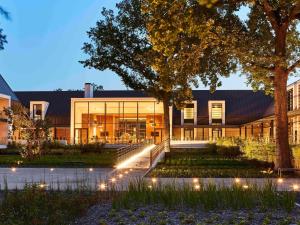 a building with lights in front of it at Le Domaine des Vanneaux Golf et Spa Mgallery in LʼIsle-Adam