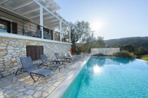 a swimming pool with chairs next to a house at VILLA BOUGARINI in Ieromónachos