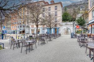 eine leere Straße mit Tischen, Stühlen und Gebäuden in der Unterkunft Le Fantastic - Quai de Grenoble / Bastille in Grenoble