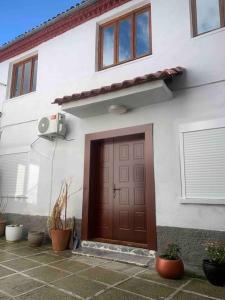 a white house with a brown door and some plants at Traditional Bazaar Home2 in Korçë