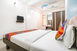 1 dormitorio con 1 cama blanca grande con almohadas coloridas en FabHotel Skylon, Near Mahatma Mandir, en Pethāpur