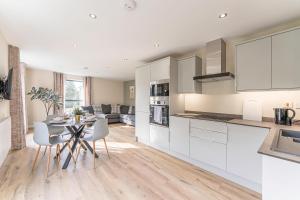 a kitchen with white cabinets and a table and chairs at Stylish 2 Bedroom Apartments in Derby in Derby
