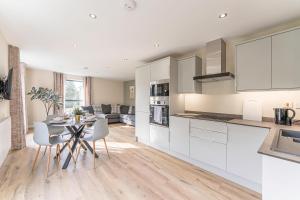 eine Küche mit weißen Schränken sowie einem Tisch und Stühlen in der Unterkunft Stylish 2 Bedroom Apartments in Derby in Derby