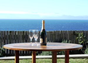 a bottle of wine on a table with two glasses at Blue Mountain Bay in Simonʼs Town