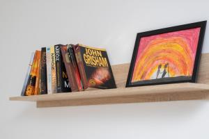 a shelf with some books and a picture at Elegant Apartment Myśliwskie Wzgórze in Gdańsk by Renters in Gdańsk