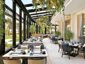 um restaurante com mesas, cadeiras e janelas em Mövenpick Hotel Bahrain em Manama