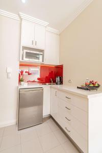 cocina con armarios blancos y detalles en rojo en Best Western Plus Camperdown Suites en Sídney