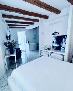 a white bedroom with a white bed and a kitchen at Hydria guest house art gallery in Acquaviva delle Fonti