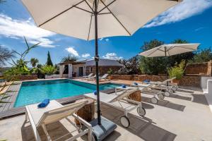 a pool with lounge chairs and an umbrella at Can White in Sant Carles de Peralta
