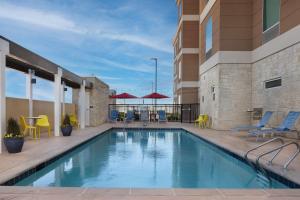 a swimming pool with chairs and tables on a building at Home2 Suites By Hilton Abilene Southwest in Abilene