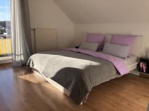 um quarto com uma cama grande com lençóis roxos e cinzentos em Ferienwohnung Am Kreuzberg für 4 Personen em Medlingen