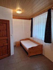 niewielka sypialnia z łóżkiem i oknem w obiekcie Pension U Martina w mieście Domažlice