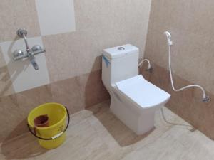 a bathroom with a toilet and a yellow bucket at YESH PALACE HOMESTAY in Khajurāho