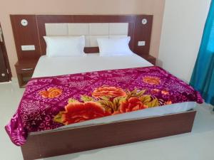 a bed with a purple bedspread with flowers on it at YESH PALACE HOMESTAY in Khajurāho
