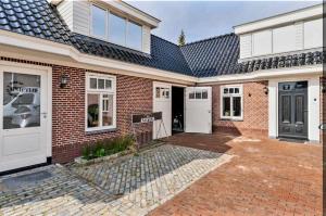 una casa in mattoni con porte bianche e un vialetto in mattoni di De Oude Smederij voor 2 personen in 't Veld a De Leijen