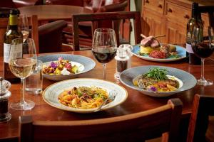 a wooden table with plates of food and wine glasses at The Glengower in Aberystwyth