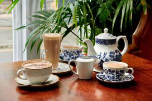 a table with three cups of coffee and a teapot at The Glengower in Aberystwyth