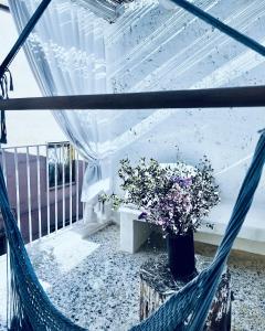 a hammock with a bench and flowers on a balcony at Hydria guest house art gallery in Acquaviva delle Fonti