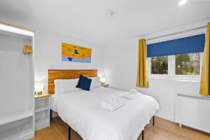 ein Schlafzimmer mit einem Bett und zwei Fenstern in der Unterkunft Crylla Valley Cottages - access to pool, gym, spa and more in Saltash + 94 Fotos