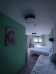 a bedroom with two beds and a green wall at Auberge du château de Joux in La Cluse et Mijoux