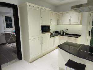 a kitchen with white cabinets and black counter tops at Whispering Pines Jumeirah Golf Estates by Golden Casa in Dubai