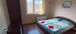 a bedroom with a bed with red pillows and a window at Къща за гости Релакс-Рaдуил in Raduil