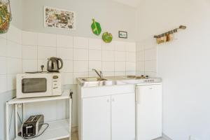 eine weiße Küche mit Mikrowelle und Spüle in der Unterkunft Chambre d'hôte La Chapelle in La Rochelle-Normande