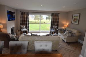 a living room with a couch and chairs and a window at Crann Mhor Holiday Home in Lochgoilhead