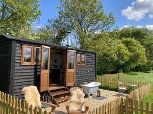 a black tiny house with a tub in a yard at Marsh Farm Glamping Shepherd Hut in Langport
