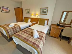 a hotel room with two beds and a desk at The Glengower in Aberystwyth