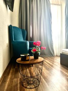 ein Wohnzimmer mit einem blauen Stuhl und einem Tisch mit Blumen in der Unterkunft Apartment Alex in Sandanski