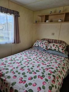uma cama com um edredão floral num quarto em J.R. Holiday Homes em Clacton-on-Sea