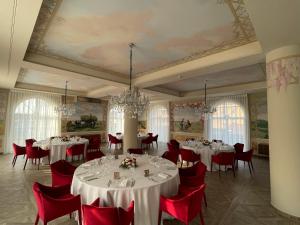 a dining room with white tables and red chairs at Accomodation Hotel Castello Il Codirosso in Cesate