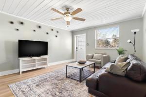 a living room with a couch and a flat screen tv at Relaxing Bungalow Walkable to the Beach! in St. Pete Beach