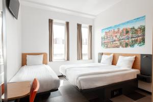 two beds in a room with two windows at easyHotel Amsterdam Arena Boulevard in Amsterdam